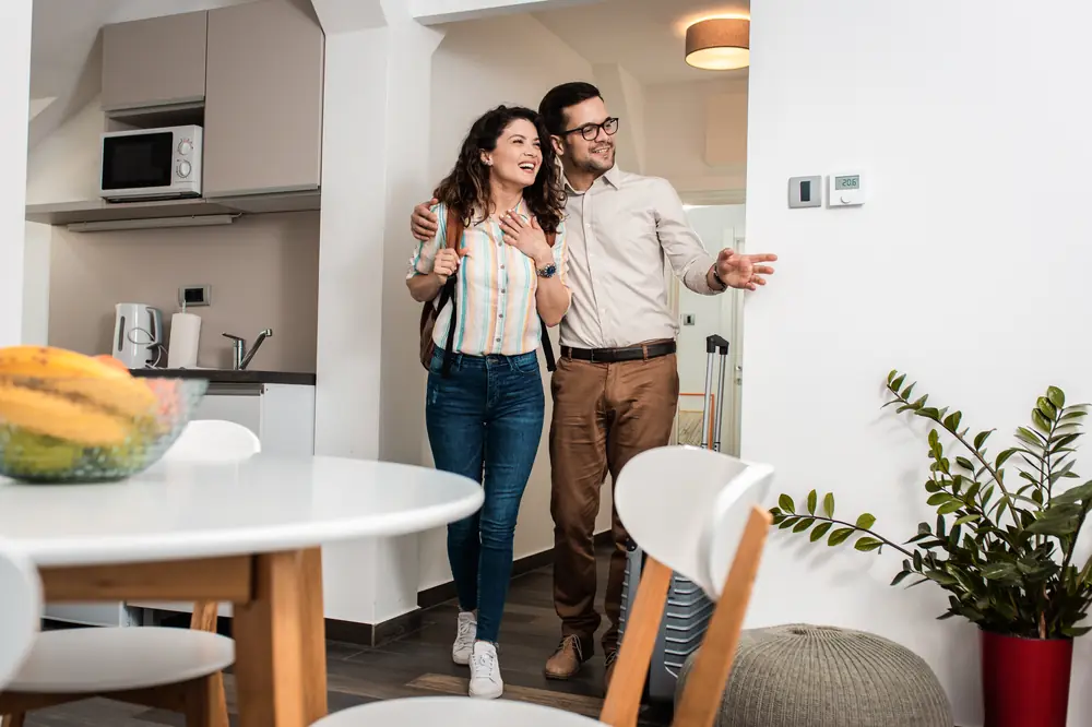 Smiling couple walking into their new home for the first time
