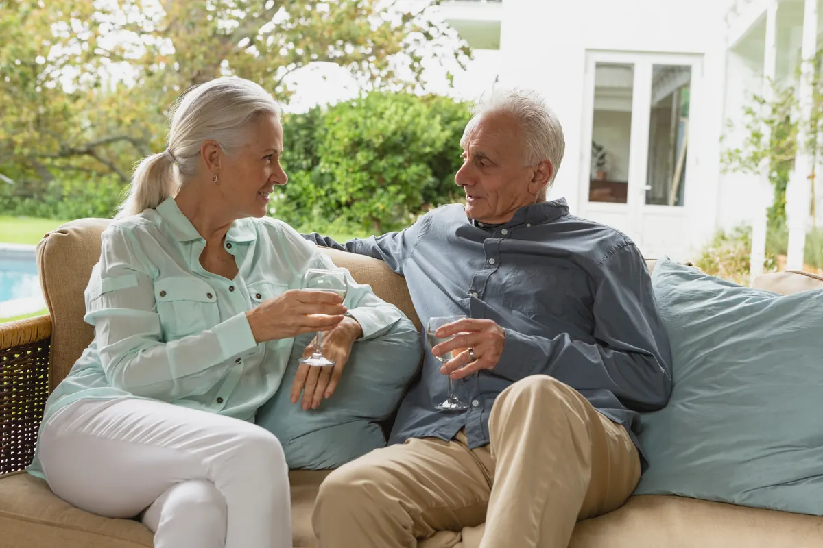 Couple in their sixties relaxing on an outdoor sofa at home