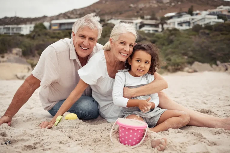 Grandparents hugging their granddaughter on the beach