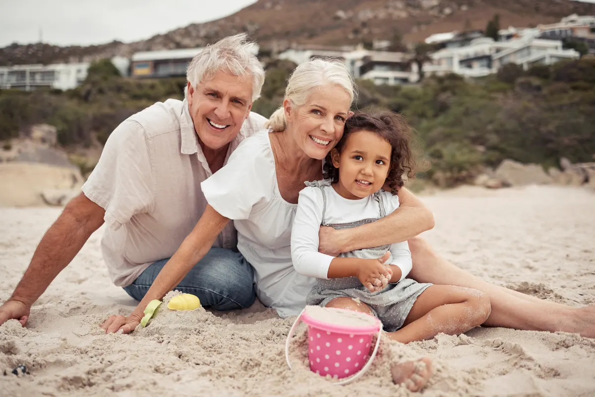 Grandparents hugging their granddaughter on the beach