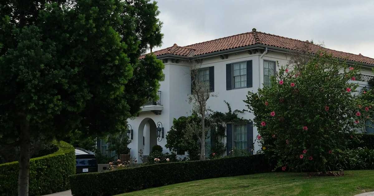 White Spanish-style home with a red tile roof and green lawn