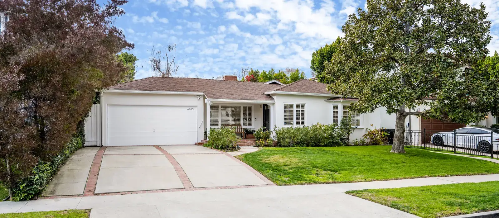 Single-story home with a green lawn on a tree-lined Southern California street