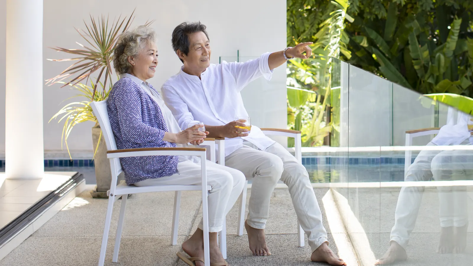 Retired couple relaxing together on a sunny patio beside their pool