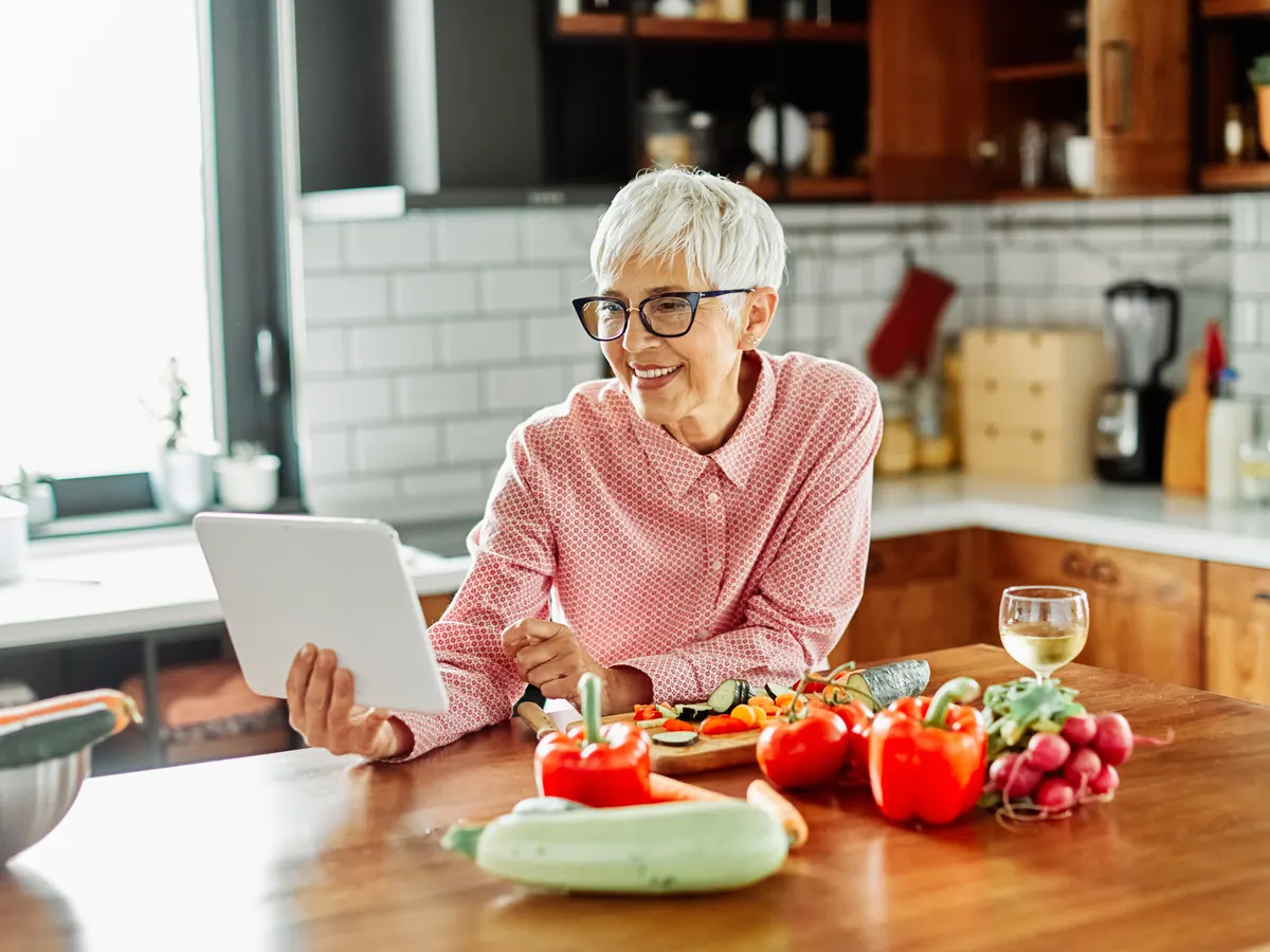 Smiling senior woman on a video call with family on a tablet in her kitchen