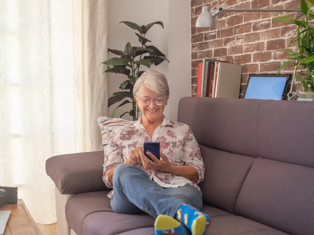 Smiling homeowner checking a smart home app on her phone in a sunny living room