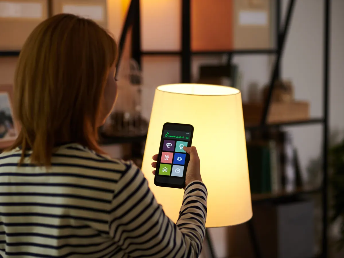 Homeowner turning on a lamp with a smart home app