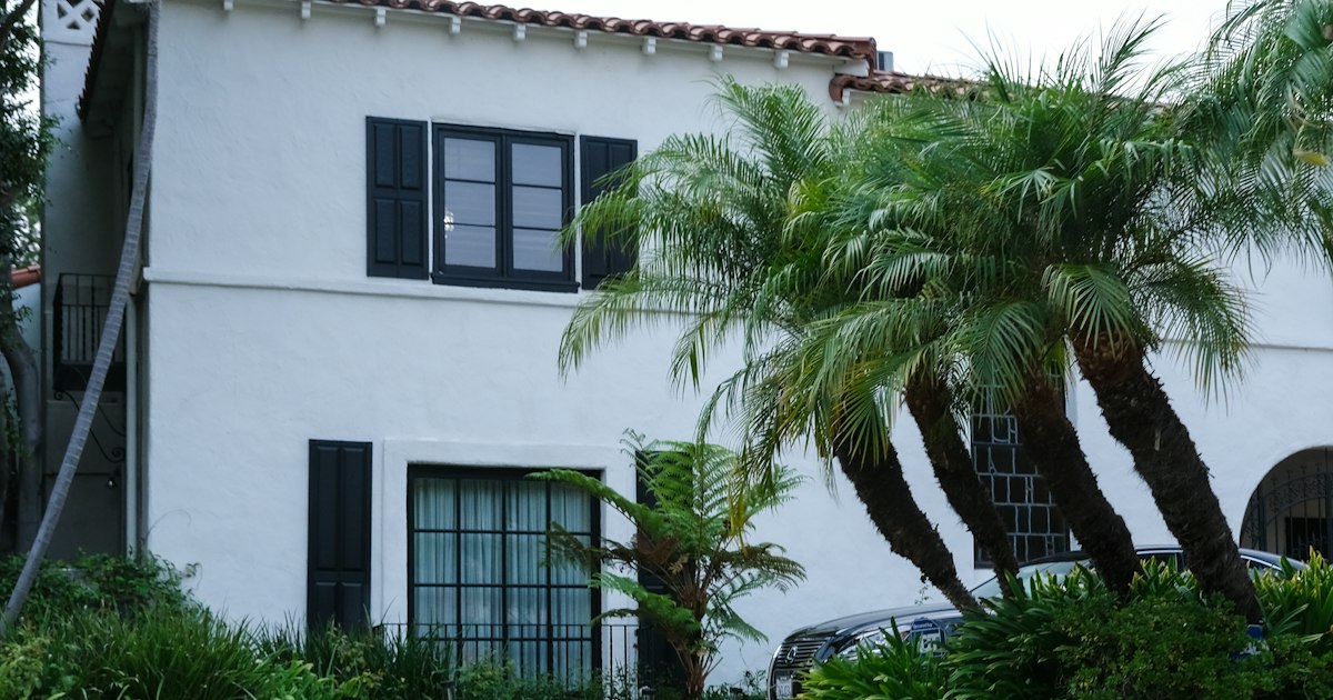 White stucco home with palm trees and green landscaping